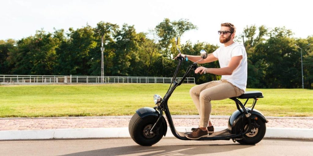 Homem casual pilotando um scooter elétrico em um ambiente ao ar livre.