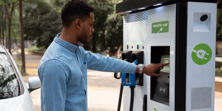 Foto de homem recarregando seu carro elétrico.