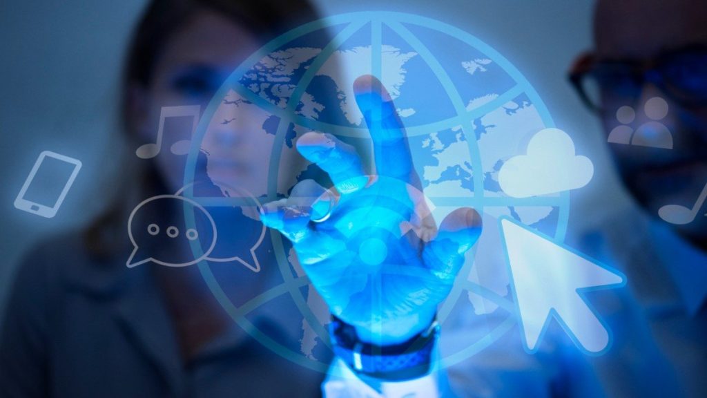 Duas pessoas interagindo com uma interface virtual holográfica azul, exibindo ícones de comunicação, nuvem e internet, simbolizando tecnologia avançada de interação digital e conectividade global.