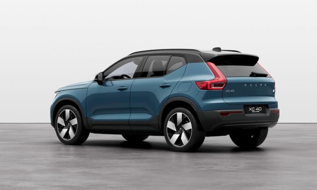 Imagem traseira de um Volvo XC40, SUV compacto, na cor azul escuro com teto preto, mostrando o design das lanternas traseiras e a linha elegante da carroceria, estacionado em um fundo cinza claro.