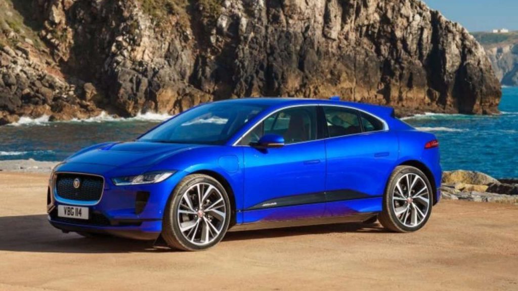 Jaguar I-PACE azul estacionado em frente a um cenário costeiro.