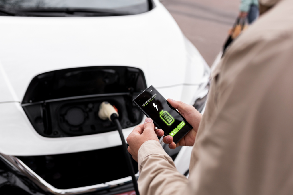 pessoa com celular na mão faz gestão de recarga de seu carro elétrico.